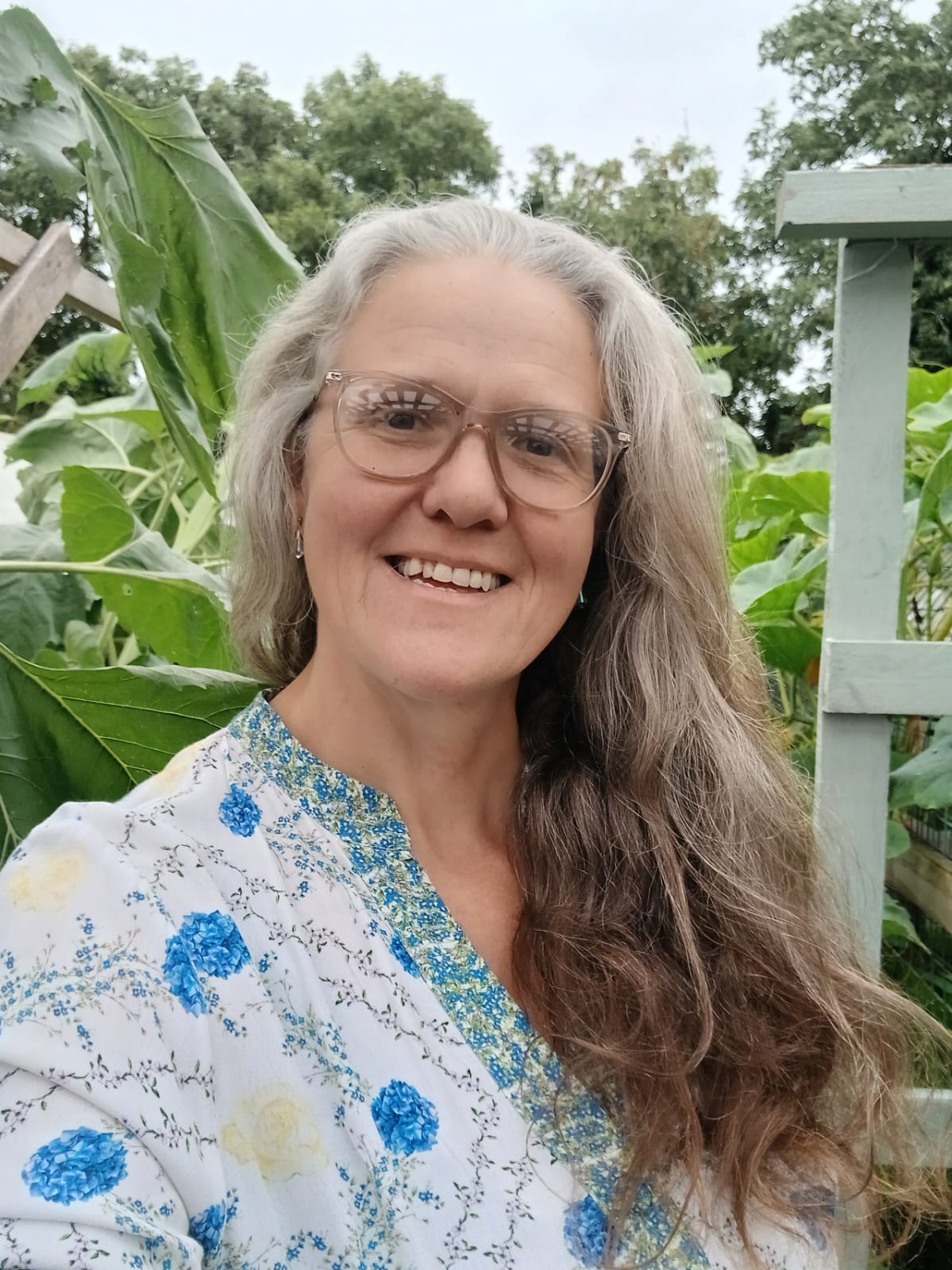 Author Sandra Nelson in a lush garden, surrounded by banana leaves and greenery.